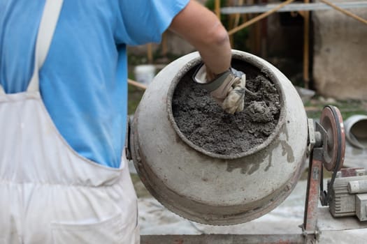 builder laborer man working with front of concrete cement mixer at construction site