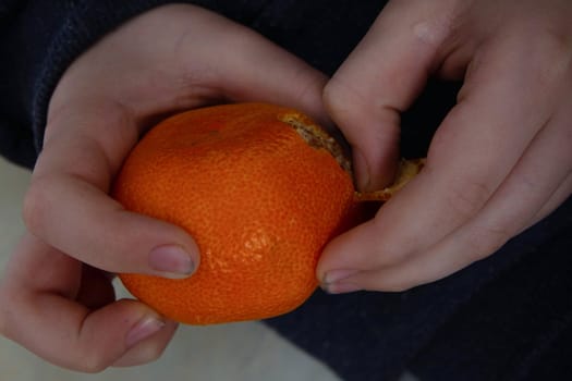 a child with dirty hands cleans a tangerine