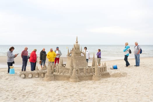 Holidaymakers admire a sandcastle on the beach of Kolobrzeg on the Polish coast of the Baltic Sea