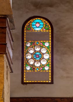 Perforated stucco window decorated with colorful stain glass with geometrical circular patterns, located at Mamluk era public historical Beshtak Palace, Moez Street, Cairo, Egypt