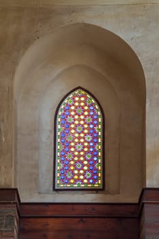 Perforated stucco window decorated with colorful stain glass with geometrical circular patterns and floral patterns, located at Mamluk era public historical Qalawun complex, Moez Street, Cairo, Egypt