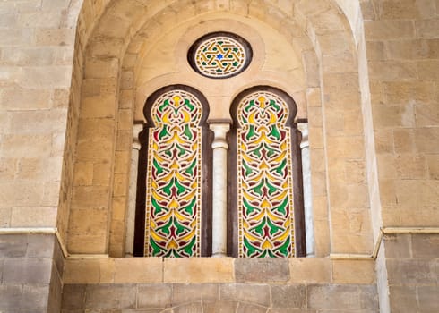 Two external adjacent perforated stucco arched windows decorated with colorful stain glass with geometrical and floral patterns, at Mamluk era public historical Qalawun complex, Cairo, Egypt