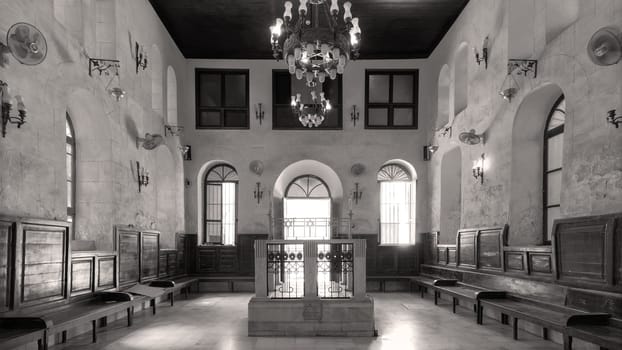 Black and white shot of interior of historic Jewish Maimonides Synagogue or Rav Moshe Synagogue with altar, arched windows and chandelier in Gamalia district, Cairo Egypt