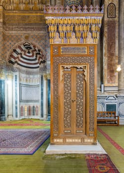 Antique wooden Minbar door with arabesque decorations tongue and groove assembled, inlaid with ivory and ebony, and Mihrab in the back, at public historical Rifaii Mosque, Royal Mosque, Cairo, Egypt