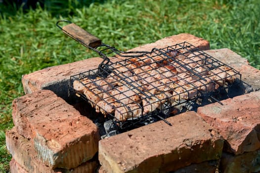 Shish kebab is fried on a grill on coals and bricks. High quality photo