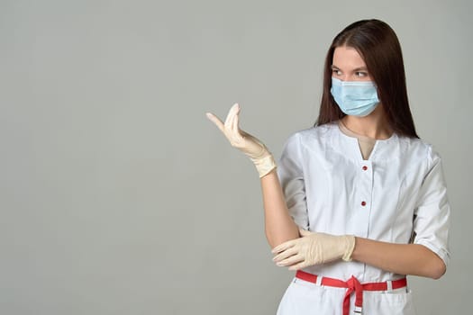 A female doctor in a medical mask points to an empty place, copy space. High quality photo