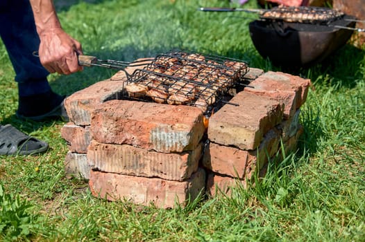Shish kebab is fried on a grill on coals and bricks. High quality photo