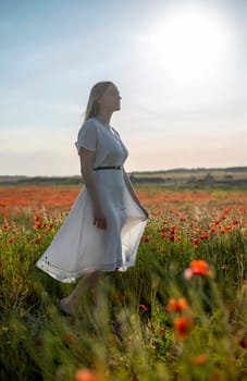 sensual young blond woman enjoying evening sun in poppy field
