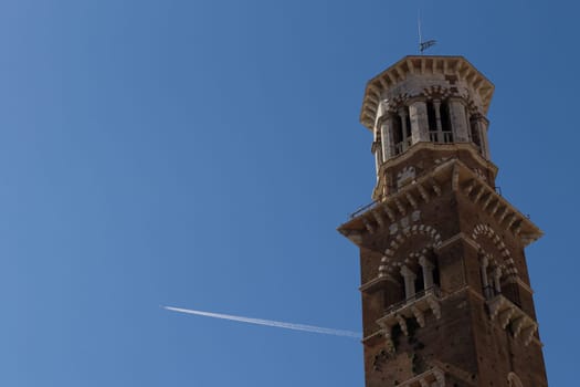 A view of Torre dei Lamberti with an airplane that cross the sky, Verona, Italy