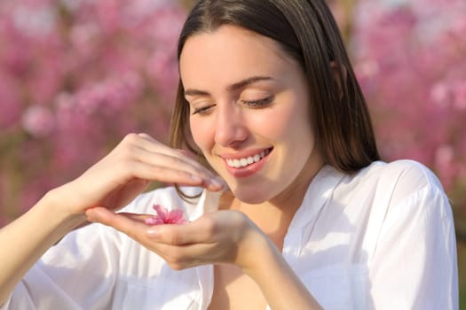 Happy woman holding and protecting flower in a pink field