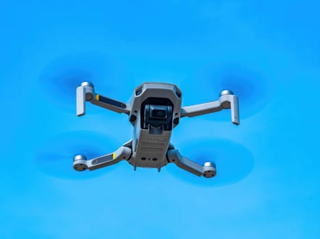 The flight of the drone against the blue sky. Drone in the air. Filming from the air. Take pictures in flight. Mini helicopter. Propeller blades. Ascend to the skies. Air space. Electronic technology.