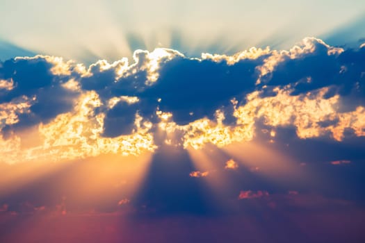 bright colored sunbeams behind the clouds