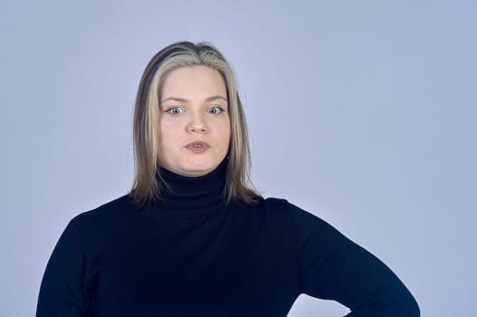 Surprised woman on a gray background in a black sweater, copy space. High quality photo