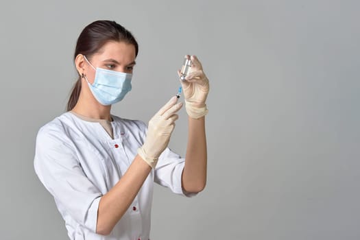 A nurse taking medicine into a syringe from a bottle close-up, a place for text. High quality photo
