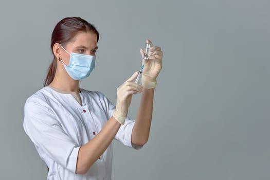 A nurse taking medicine into a syringe from a bottle close-up, a place for text. High quality photo