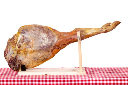 Spanish food. Closeup of a front leg of a Spanish Serrano ham on a wooden stand on a red checkered tablecloth isolated on a white background. Template for your design.