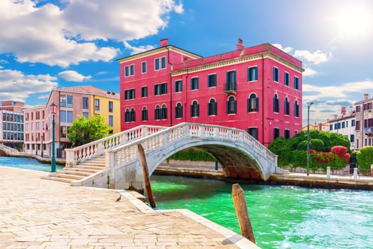 Bridge of Venice near a typical old palace, view from the canal, Italy.