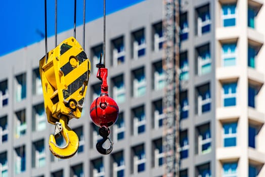 Hooks of crane on construction site with building and sky in background