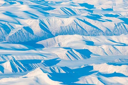 Snow mountains and planes of Greenland. View from plane.