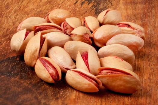 Turkish red pistachios on wooden desk, closeup on roasted nuts.