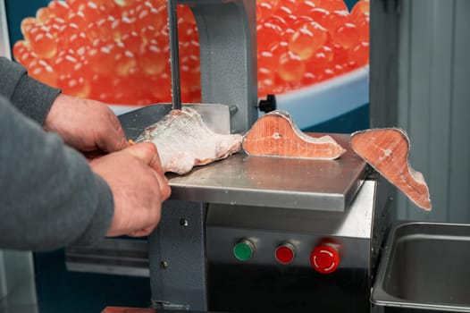 Service for cutting frozen salmon fish on a steak in a fish supermarket using professional equipment