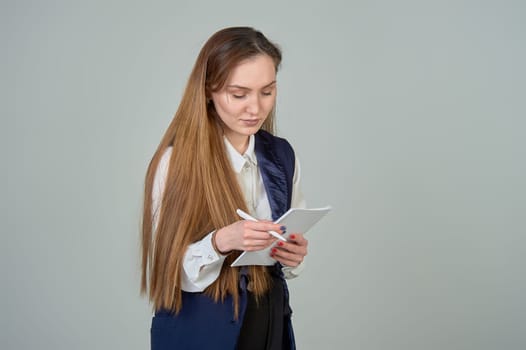 A young woman reads on a notepad with a pen in her hands on a background with a place to insert it. High quality photo
