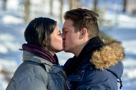Young couple kissing outdoors in a winter park close up. High quality photo