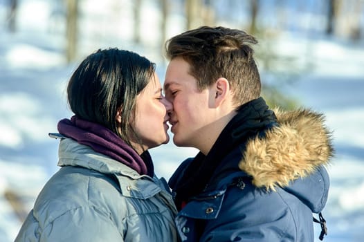 Young couple kissing outdoors in a winter park close up. High quality photo
