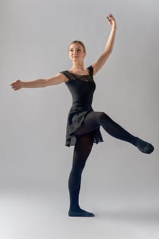 the ballerina stands on one leg with her hands raised. High quality photo