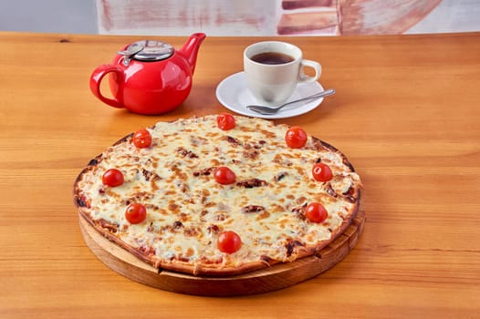 pizza Lombardy lies on a stand with tea and a kettle. High quality photo