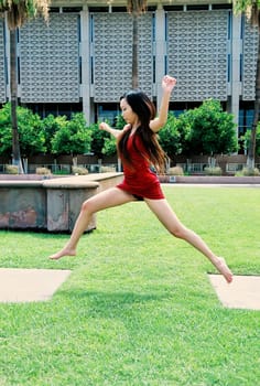 A lovely Asian female model jumping outdoors
