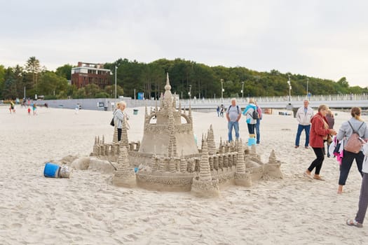Holidaymakers admire a sandcastle on the beach of Kolobrzeg on the Polish coast of the Baltic Sea