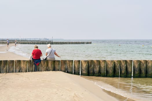 two old vacationers on a breakwater at the beach of Kolobrzeg at the Baltic Sea in Poland