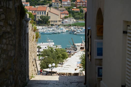 View through a narrow alley to the port of the town of Rab in Croatia