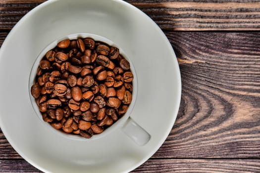 A white coffee mug filled with fragrant coffee beans stands on an old tree. High quality photo