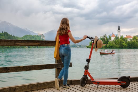 Female traveler using electric scooter as modern ecological mean of transport while exploring green country Slovenia at vacations. Green eco energy concept with zero emission