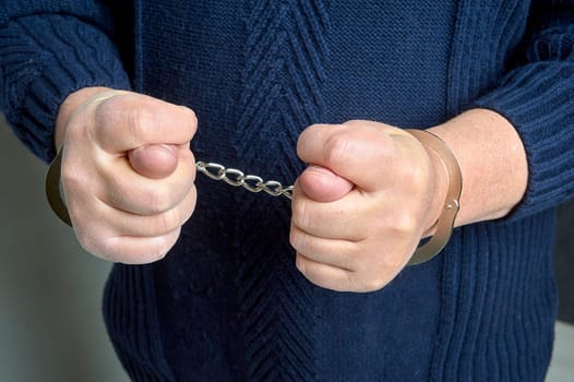 men's hands in handcuffs show a fig. High quality photo