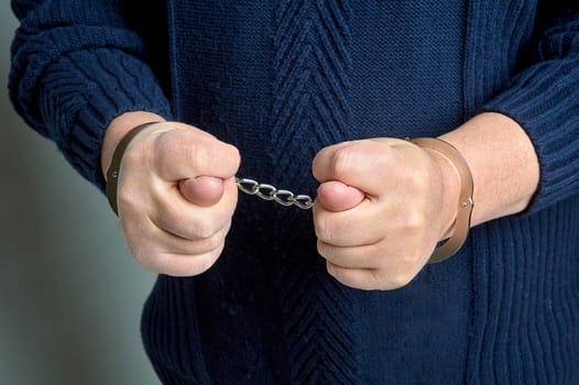 men's hands in handcuffs show a fig. High quality photo