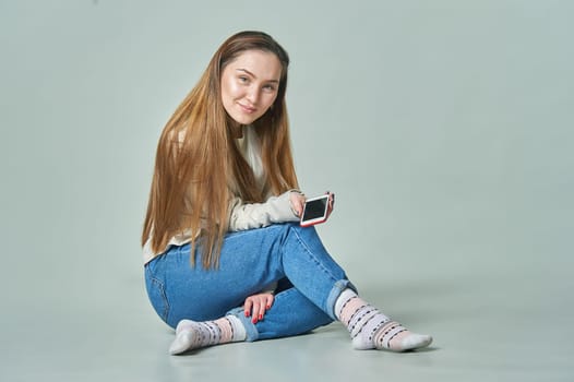 A girl sits in the background with a phone in her hands and smiles. High quality photo