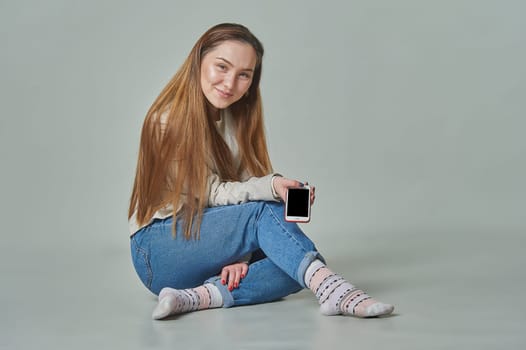 A girl sits in the background with a phone in her hands and smiles. High quality photo