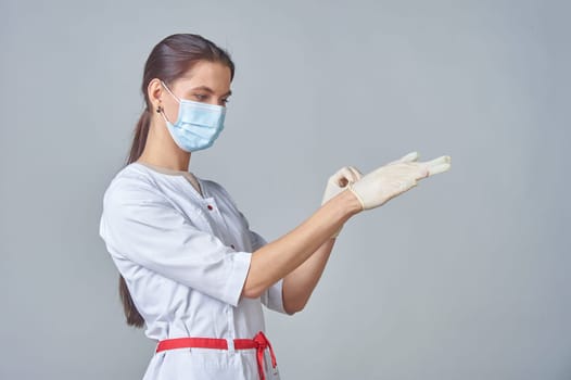 a nurse in a medical mask wearing medical gloves in a white coat. High quality photo