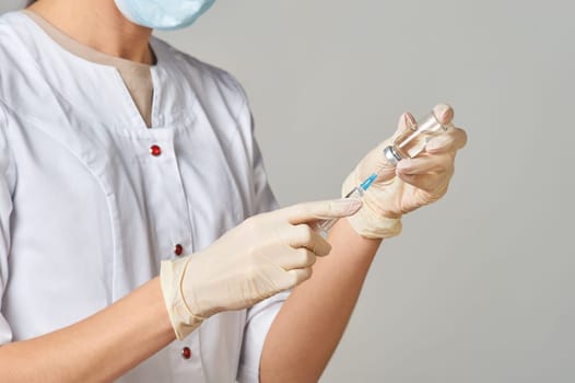 A nurse taking medicine into a syringe from a bottle close-up. Preparation of the coronavirus vaccine-Covid-19. High quality photo