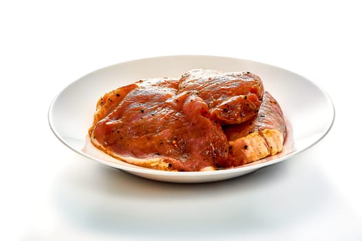 Pork in marinade lies on a white plate on a white isolated background. High quality photo