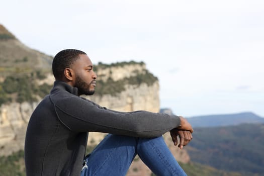 Profile of a serious man with black skin contemplating sitting in the mountain