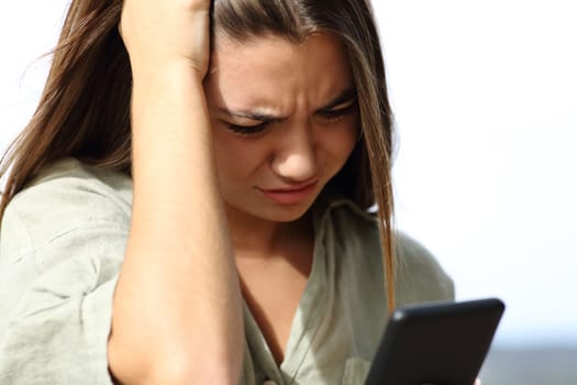 Worried teen complaining checking news on smart phone outdoors