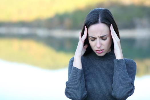 Front view portrait of a woman suffering migraine in a lake