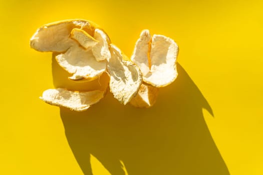 Orange peel on a yellow background in bright light.