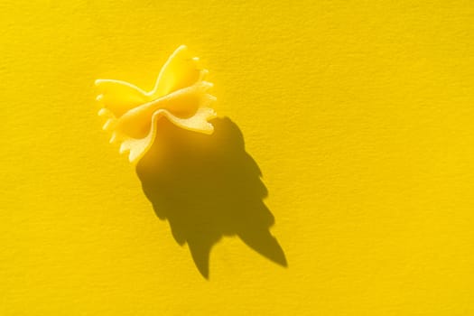 Close-up of farfalle. paste on a yellow background in bright light
