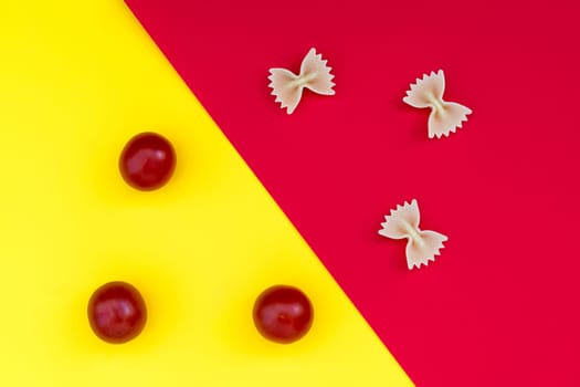 Three pieces of farfalle paste and three cherry tomatoes on a contrasting background
