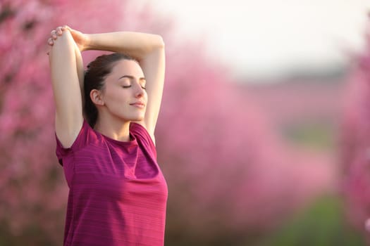 Sportswoman stretching arms and relaxing in a field after sport